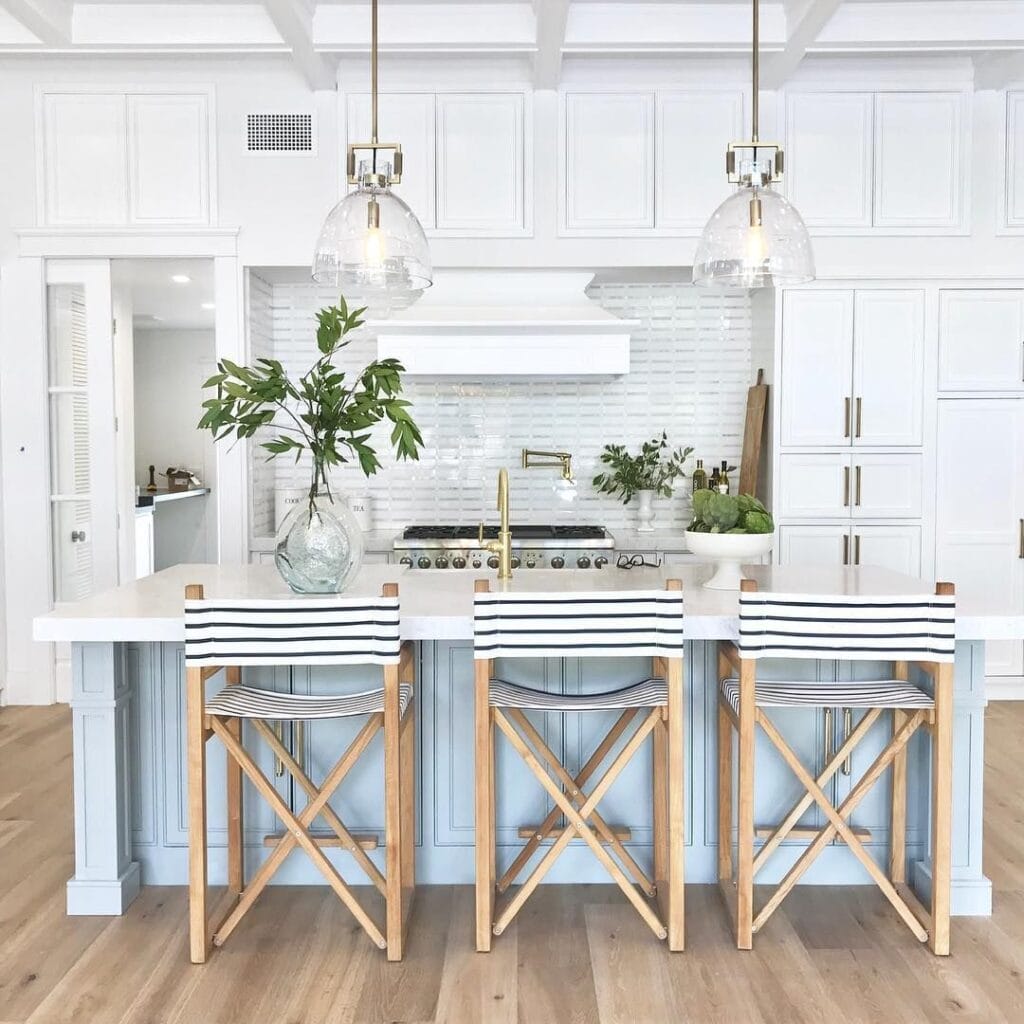 Coastal kitchen with striped chairs, white cabinets, and gold fixtures used in vacation rental upgrades Cape Cod homes